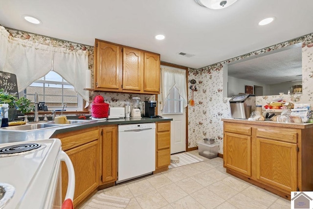 kitchen with white dishwasher, recessed lighting, a sink, visible vents, and wallpapered walls