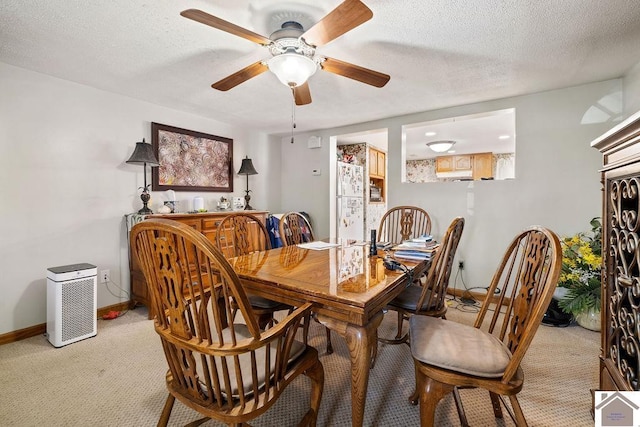 dining space with a textured ceiling, ceiling fan, light carpet, and baseboards