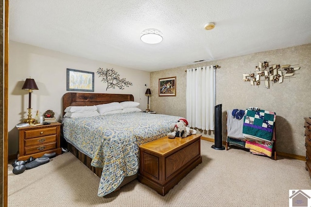 bedroom featuring light carpet, visible vents, and a textured ceiling