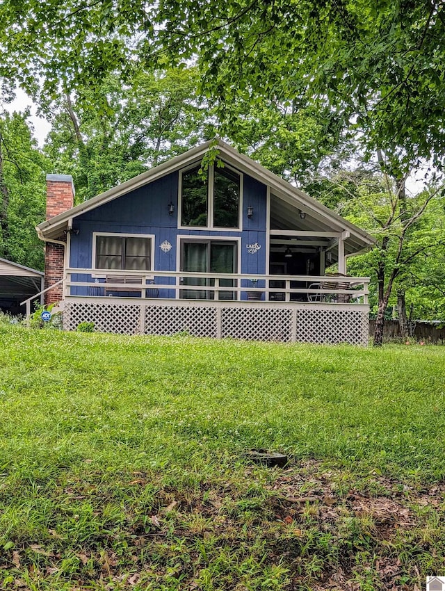 view of front facade with a deck, a front lawn, and a chimney