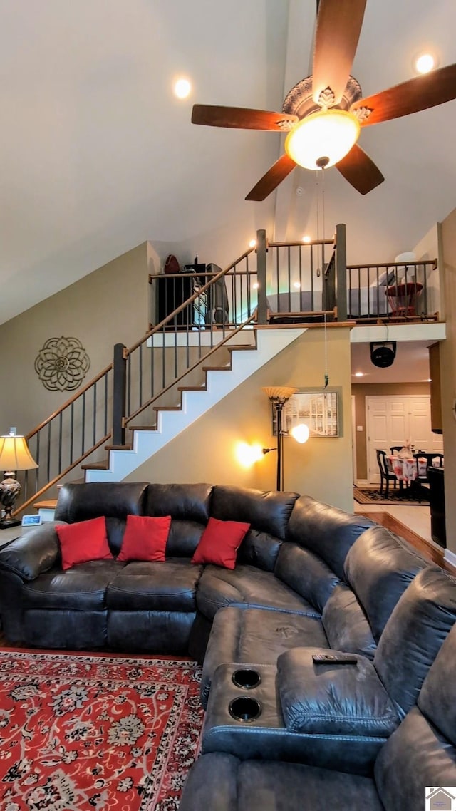 living room with ceiling fan, a high ceiling, and stairway