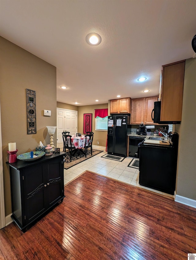 kitchen with light wood finished floors, baseboards, a sink, and black fridge with ice dispenser