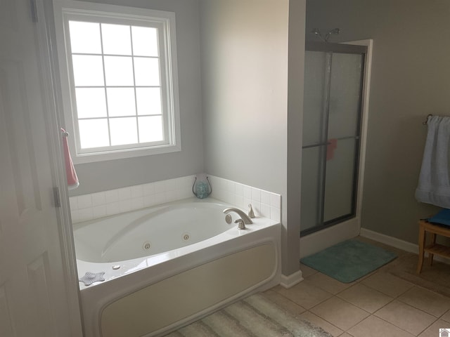 bathroom with tile patterned flooring, a jetted tub, a shower stall, and baseboards