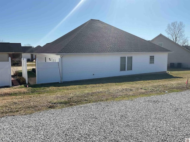 view of side of property featuring a shingled roof and a lawn