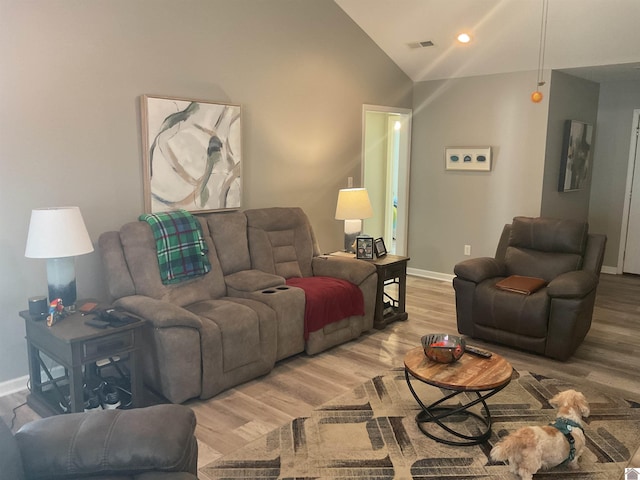 living room featuring visible vents, baseboards, vaulted ceiling, and wood finished floors