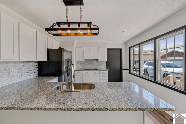 kitchen with tasteful backsplash, stainless steel fridge with ice dispenser, light stone counters, white cabinetry, and a sink