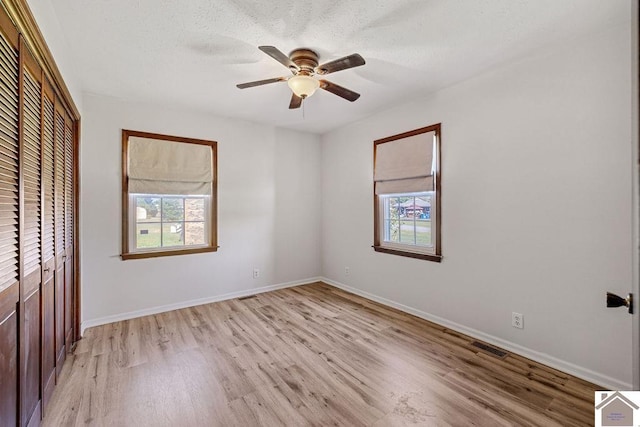 unfurnished bedroom featuring light wood-style floors, a closet, ceiling fan, and baseboards