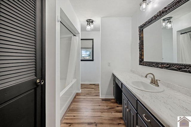 bathroom with shower / bath combination with curtain, vanity, baseboards, and wood finished floors