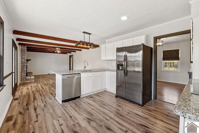 kitchen featuring appliances with stainless steel finishes, white cabinetry, a sink, and a peninsula