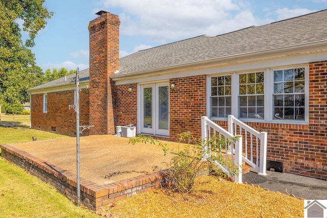 rear view of house featuring a patio, brick siding, a shingled roof, crawl space, and a chimney