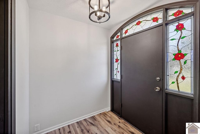 foyer with a chandelier, baseboards, and light wood finished floors