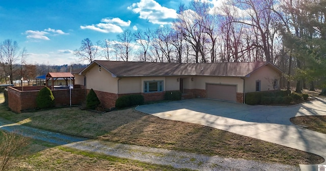 ranch-style home featuring concrete driveway, brick siding, an attached garage, and stucco siding