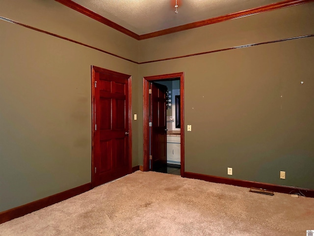 carpeted spare room featuring a textured ceiling, baseboards, and crown molding