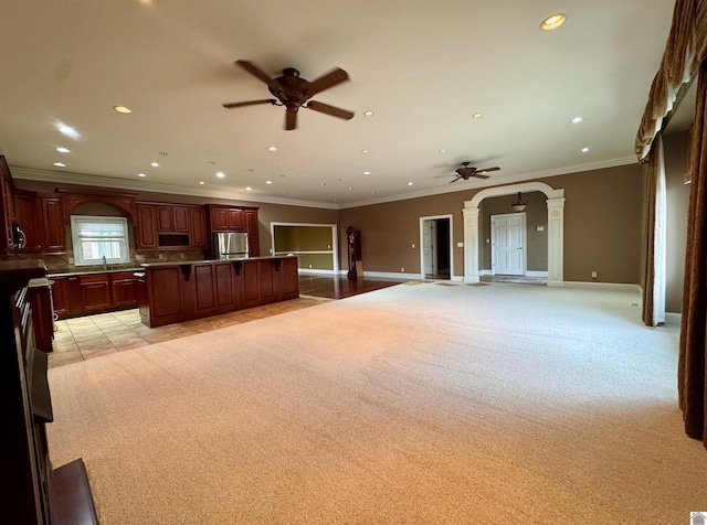 kitchen featuring decorative columns, arched walkways, a breakfast bar area, stainless steel refrigerator, and open floor plan