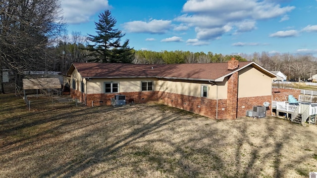 view of side of home featuring stucco siding, a chimney, central AC unit, and brick siding