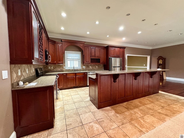 kitchen with a kitchen breakfast bar, baseboards, appliances with stainless steel finishes, ornamental molding, and tasteful backsplash