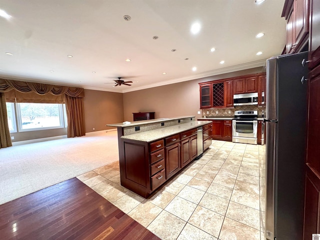 kitchen featuring recessed lighting, open floor plan, appliances with stainless steel finishes, decorative backsplash, and crown molding