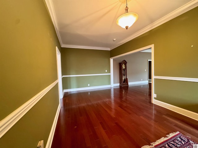 empty room featuring baseboards, wood finished floors, and crown molding