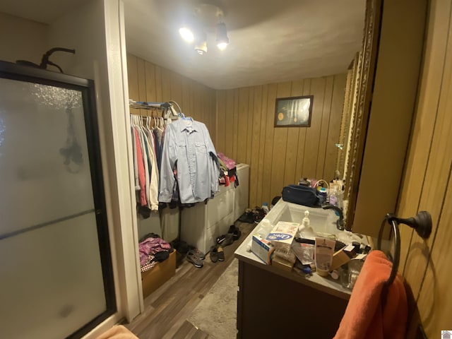 full bath featuring a shower stall, wooden walls, wood finished floors, and vanity