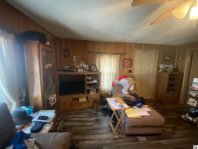 living room featuring ceiling fan, wooden walls, and wood finished floors