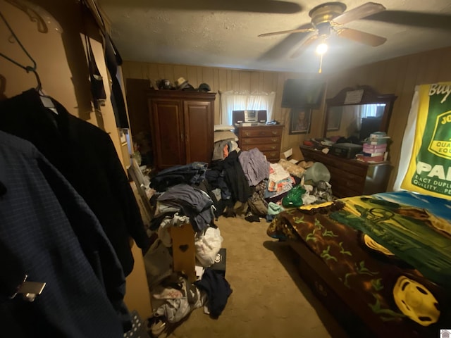 bedroom featuring wood walls, carpet, ceiling fan, and a textured ceiling