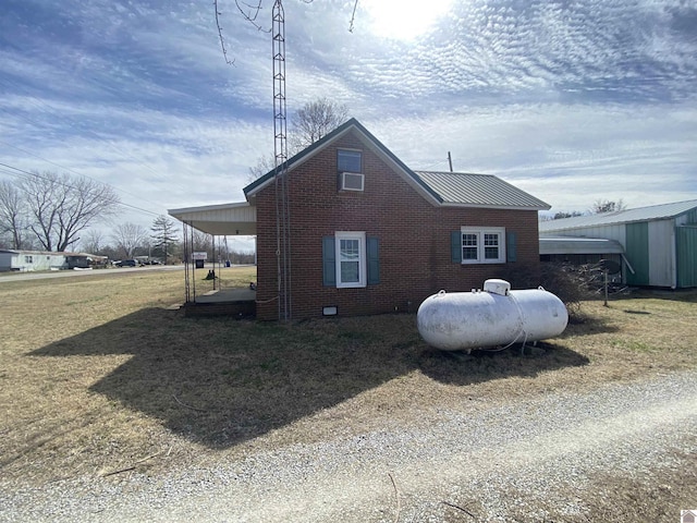 view of side of property with an outbuilding, metal roof, brick siding, and a lawn