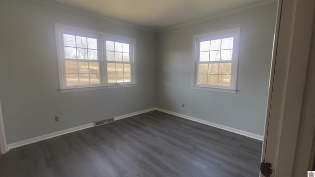 spare room featuring ornamental molding, visible vents, dark wood finished floors, and baseboards