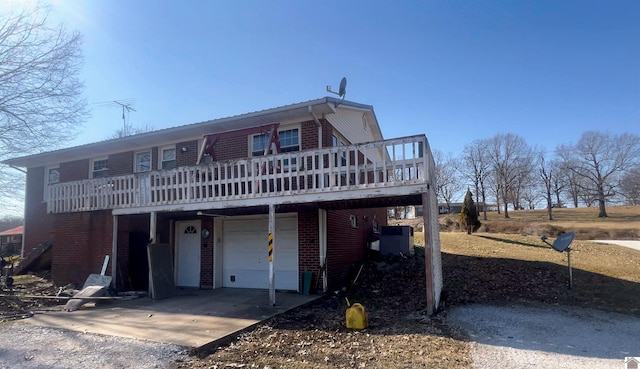 view of front of house with driveway, brick siding, central AC unit, and a wooden deck