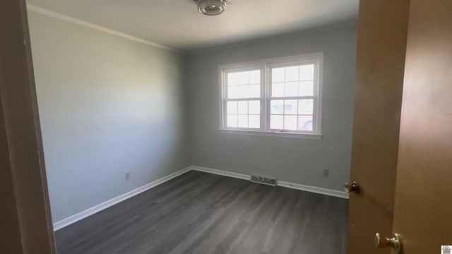 spare room featuring crown molding, dark wood-style flooring, visible vents, and baseboards