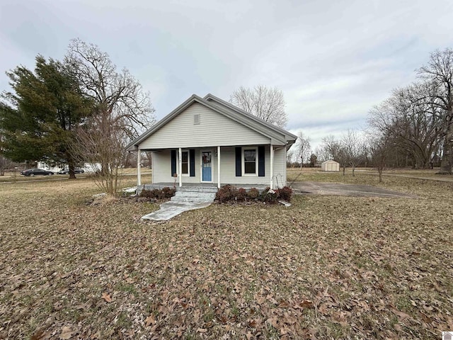 bungalow featuring a shed, a porch, and an outdoor structure