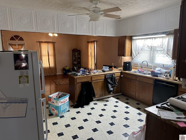 kitchen featuring a textured ceiling, a sink, a ceiling fan, black dishwasher, and freestanding refrigerator