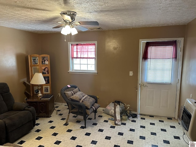 interior space featuring heating unit, a ceiling fan, visible vents, and a textured ceiling