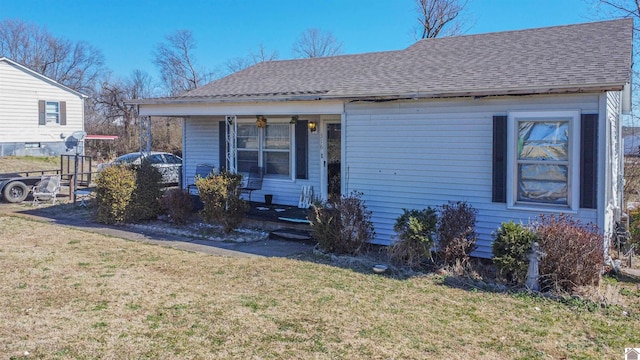 view of front facade with covered porch, a shingled roof, and a front lawn