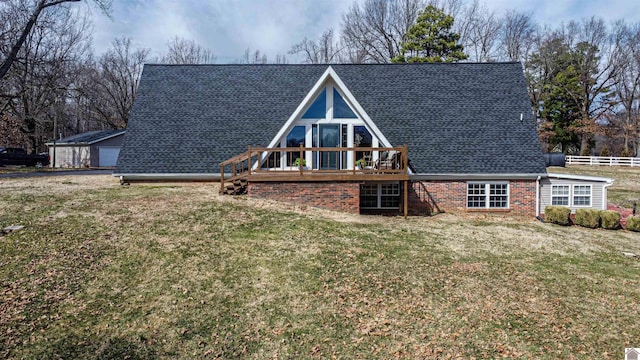 view of front facade featuring a shingled roof, fence, a wooden deck, a front lawn, and brick siding