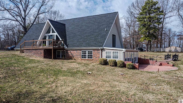 rear view of house with a patio, a deck, a lawn, and brick siding