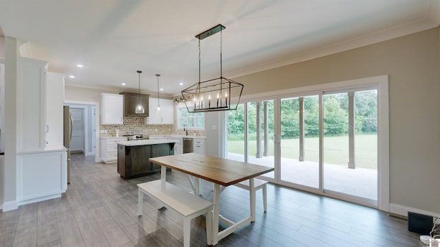 kitchen with a kitchen island, light countertops, stainless steel dishwasher, tasteful backsplash, and crown molding