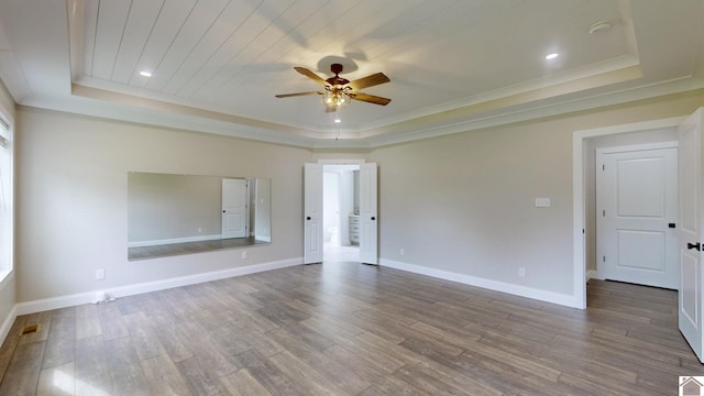 unfurnished room with a tray ceiling, visible vents, ceiling fan, wood finished floors, and baseboards