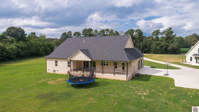 view of front of property with concrete driveway, brick siding, a patio, and a front lawn