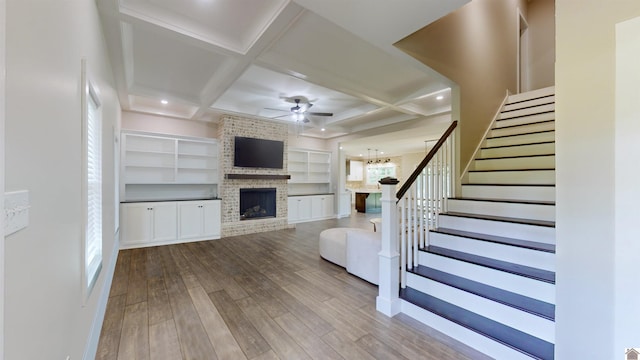 unfurnished living room with coffered ceiling, a fireplace, stairway, and wood finished floors