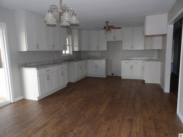 kitchen with ceiling fan with notable chandelier, dark wood finished floors, light stone countertops, and white cabinets