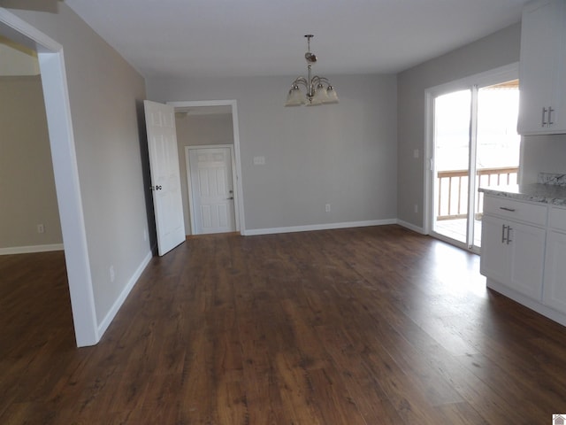 unfurnished dining area with dark wood-style floors, a chandelier, and baseboards