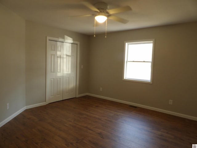 unfurnished bedroom with visible vents, a closet, baseboards, and dark wood-type flooring