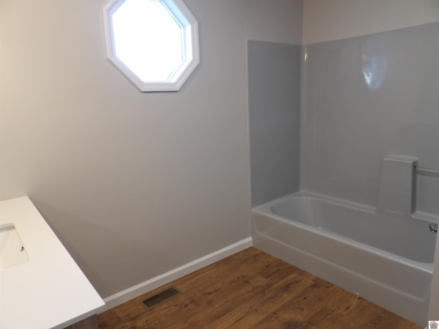 full bathroom featuring wood finished floors, vanity, visible vents, baseboards, and  shower combination