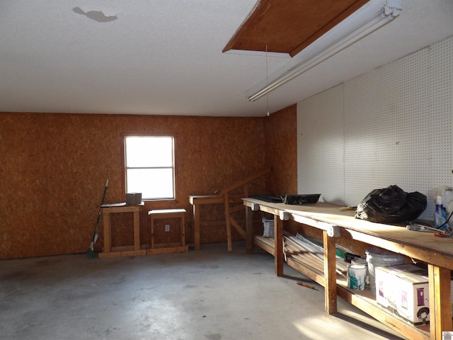 interior space featuring attic access, unfinished concrete flooring, and a workshop area