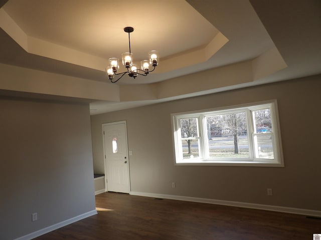 unfurnished room with a chandelier, a raised ceiling, dark wood finished floors, and baseboards