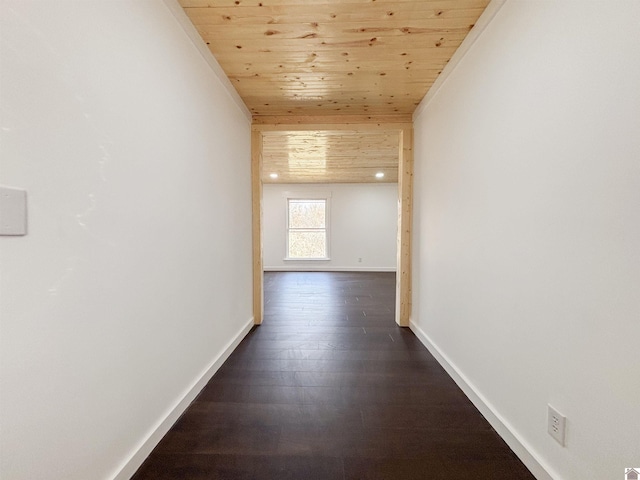 hallway with dark wood-type flooring, wood ceiling, and baseboards