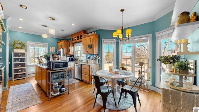 kitchen featuring brown cabinetry, appliances with stainless steel finishes, ornamental molding, light wood-style floors, and a sink