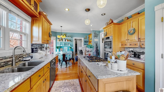 kitchen featuring light stone counters, a center island, a notable chandelier, appliances with stainless steel finishes, and a sink