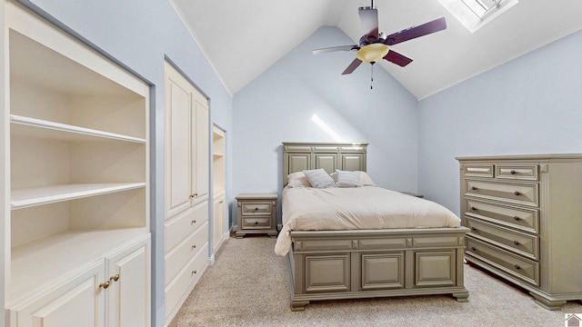 bedroom featuring vaulted ceiling with skylight, ceiling fan, and light colored carpet