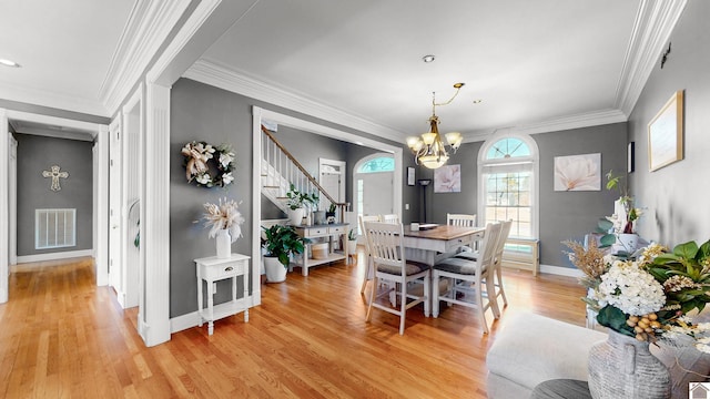 dining space with light wood finished floors, baseboards, visible vents, ornamental molding, and an inviting chandelier